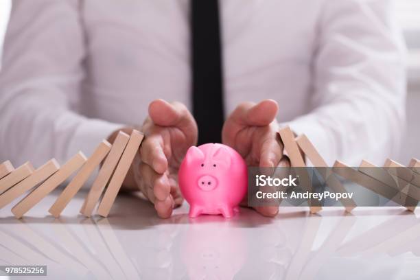 Human Hand Protecting Piggybank From Falling Wooden Blocks Stock Photo - Download Image Now