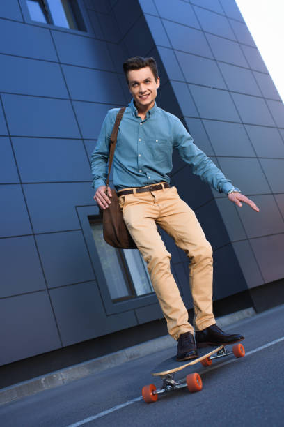 istock handsome smiling young man riding skateboard on street 978525360
