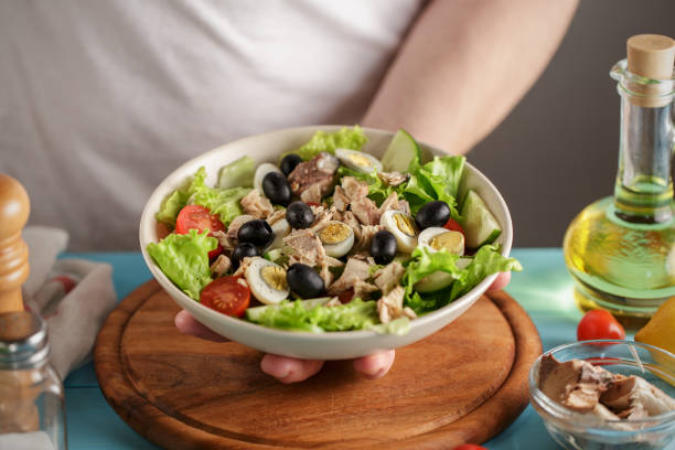 istock Chef serves bowl with tuna salad, cherry tomatoes and olives. 978539984