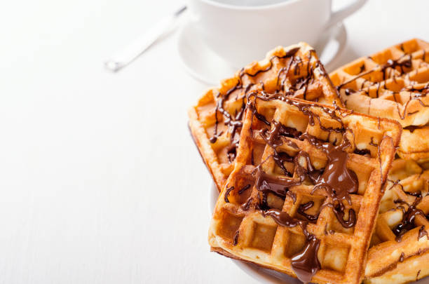 Belgian waffles on a plate of chopped chocolate on a white background. Sweets, dessert. Copy space.
