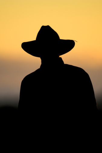 A Cowboy stands in the late afternoon light making a silhouette