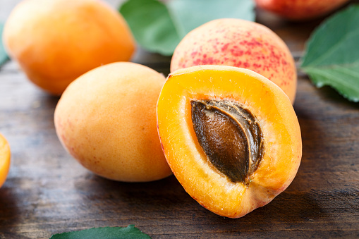 ripe apricots close-up on a wooden background with green leaves