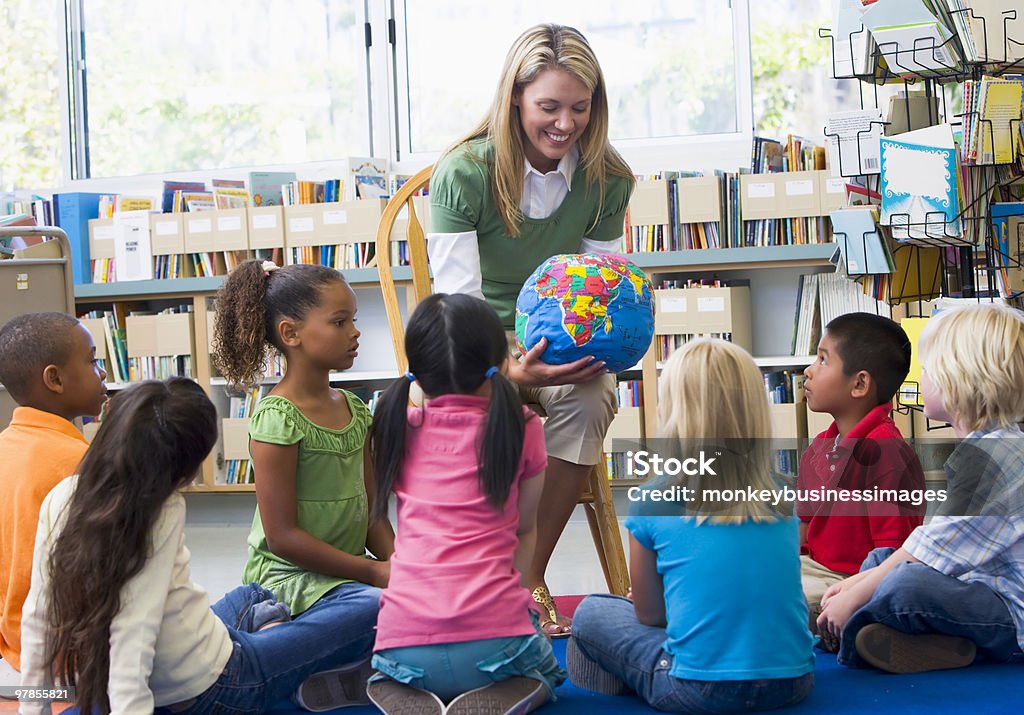 Kindergarten teacher and children looking at globe  Globe - Navigational Equipment Stock Photo