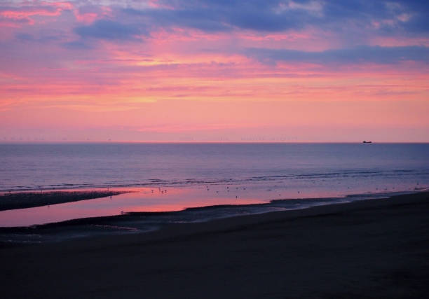 hermosa cerca de crepúsculo oscuro sobre un tranquilo mar plano con cielo púrpura y azul nubes reflejada en el agua en la playa - horizon over water england uk summer fotografías e imágenes de stock