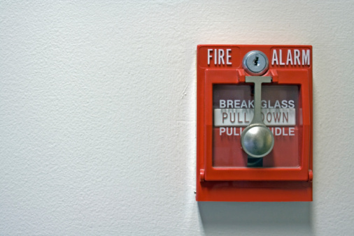 A close-up photo of a bright red fire alarm with space for text on the left