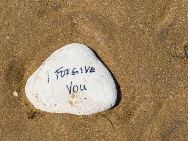 Isolated Stone with written proverb message on it White stone in sand with proverb message written on it forgiveness stock pictures, royalty-free photos & images