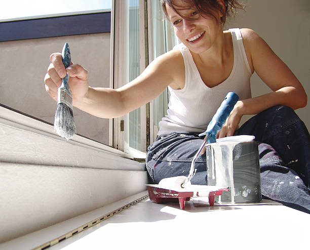 Young woman washing her windows with a smile