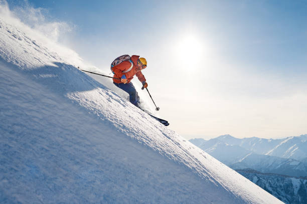 skier rides freeride on powder snow down slope against the backdrop of the mountains stock photo