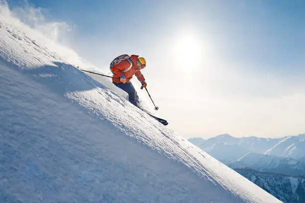 skier rides freeride on powder snow down the slope against the backdrop of the mountains