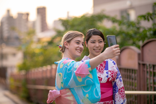 Multi-ethinic group of friends in yukata taking picture on slope
