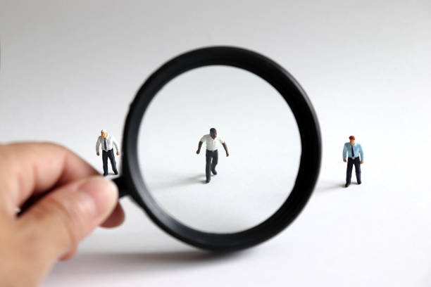 A concept of unfair social prejudice. The miniature men and a magnifying glass. stock photo
