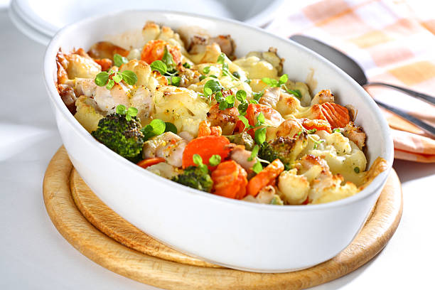 A white dish of baked mixed vegetables on a cutting board
