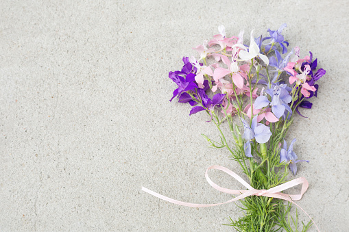 Pastel bouquet of wild flowers & bow on grey stone copy space.