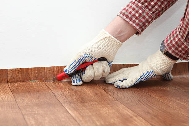 Person wearing gloves cutting linoleum with knife stock photo