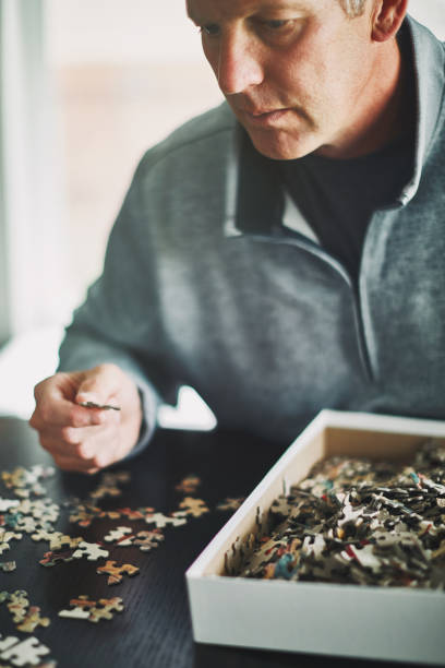 istock Mature man at home working on jigsaw puzzle 978775164