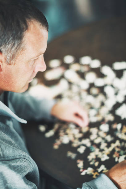 istock Mature man at home working on jigsaw puzzle 978775562