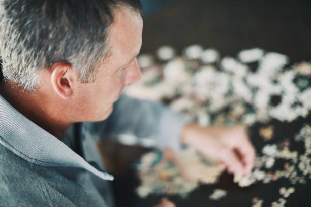 istock Mature man at home working on jigsaw puzzle 978776214