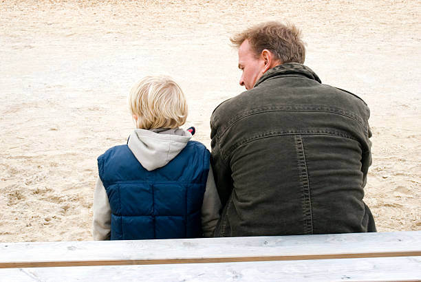 father and son sitting together stock photo