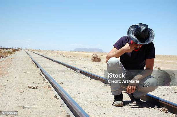 Mann Sitzt Auf Der Eisenbahn Und Rauchen Stockfoto und mehr Bilder von Blick nach unten - Blick nach unten, Cowboy, Autoreise