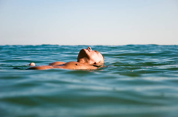 man floating in water. stock photo