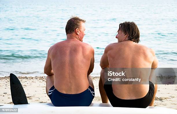 Due Uomini Seduti Insieme Sulla Spiaggia - Fotografie stock e altre immagini di 40-44 anni - 40-44 anni, Adulto, Adulto in età matura