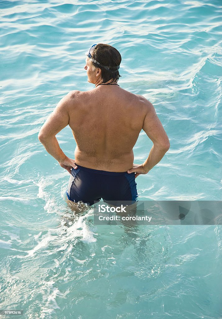 man standing in turquoise water  Swimming Trunks Stock Photo