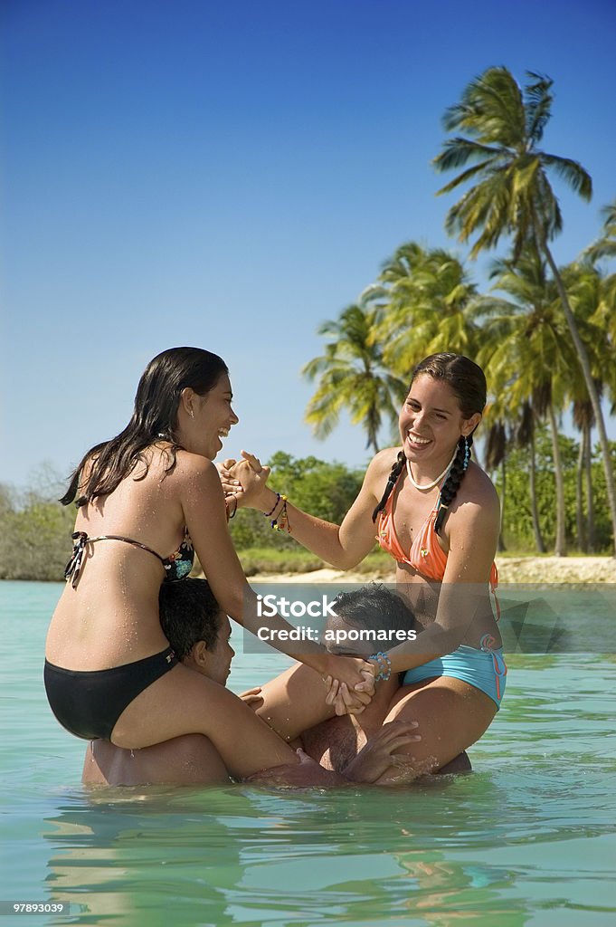 Friends playing in the beach four (4) friends having a good time in a turquoise Tropical island beach. Adolescence Stock Photo