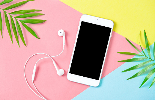 Summer holidays flat lay background. Mobile phone with headphones