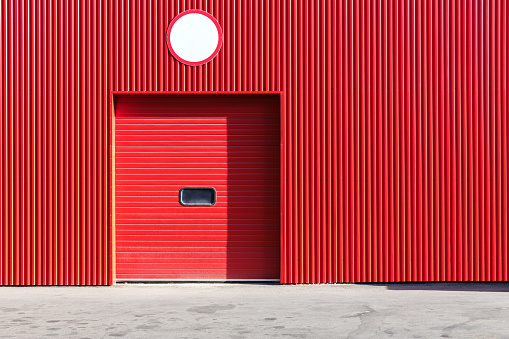 red metal warehouse wall with closed roller shutter door
