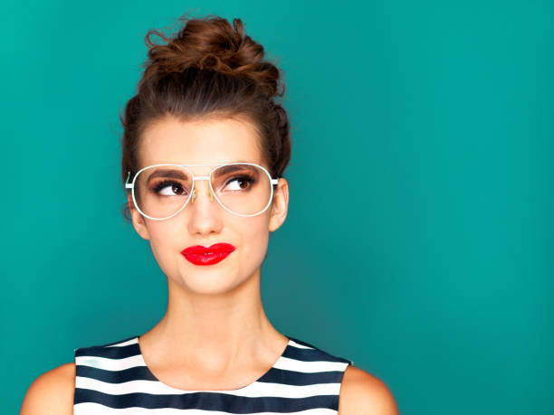 Now that's an idea Studio shot of a beautiful young woman posing against a turquoise background multi coloured glasses stock pictures, royalty-free photos & images