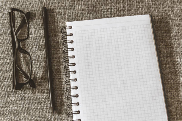 istock Top view goals list with notebook, pencil, glasses on grey fabric. Flat lay, copy space 978985920