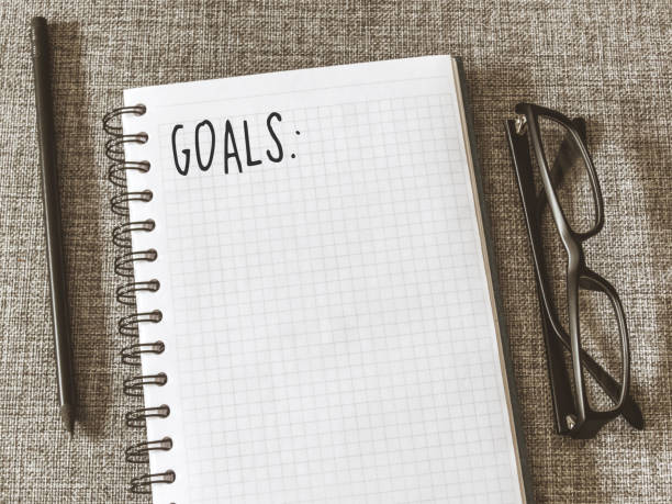 istock Top view goals list with notebook, pencil, glasses on grey fabric. Flat lay, copy space 978985958