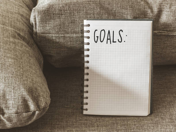istock Top view goals list with notebook, cup of coffee on on grey fabric. Flat lay, copy space 978986058