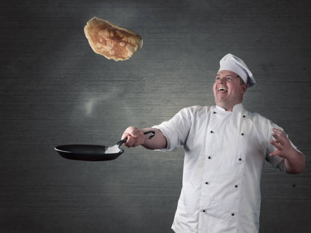 chef turns fresh pancakes in the pan stock photo