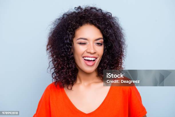 Portrait Of Cheerful Joyful Woman In Orange Outfit With Modern Hairdo Winking With One Eye Looking At Camera Isolated On Grey Background Affection Dream Feelings Concept Stock Photo - Download Image Now