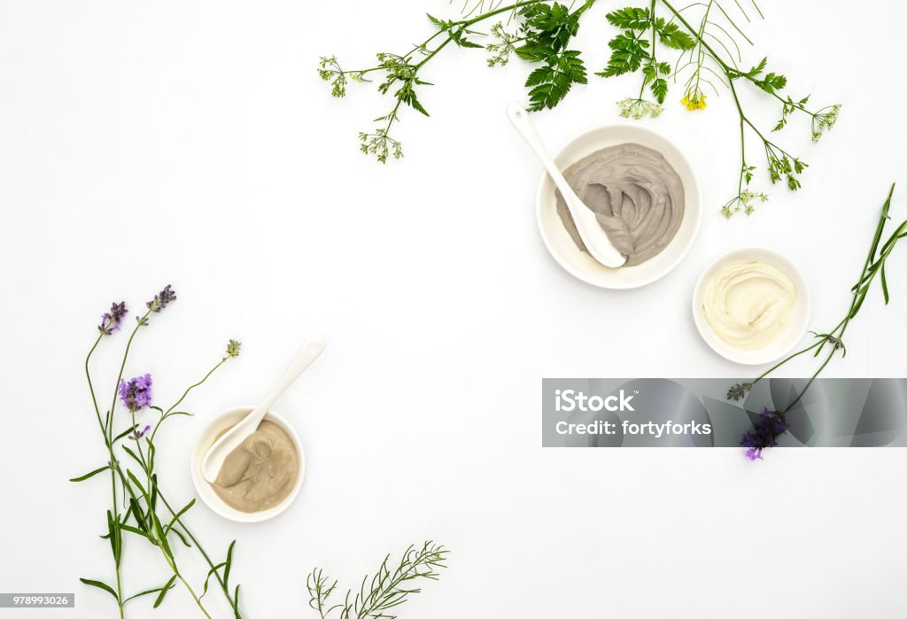 Natural cosmetics concept with various kinds of cosmetic clays and herbs Natural cosmetics concept with various kinds of cosmetic clays ready for spa treatment decorated with healing summer herbs, flat lay composition with blank space for a text Spa Stock Photo