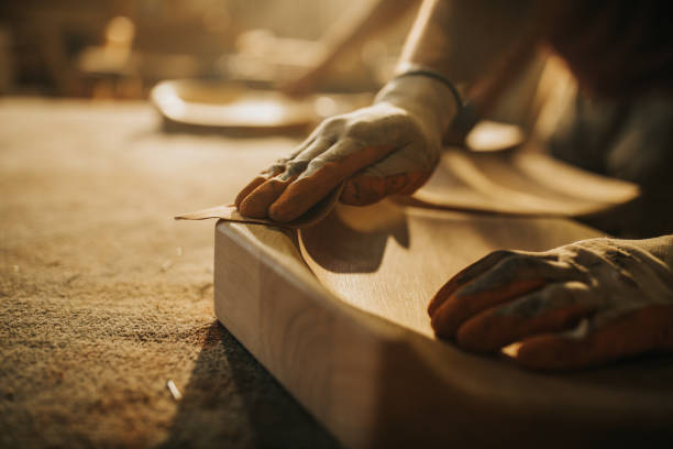 Close up of unrecognizable carpenter restoring a wood with sand paper. Close up of unrecognizable manual worker using sand paper while working on a wood. sand paper stock pictures, royalty-free photos & images