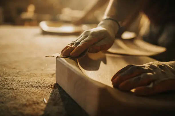 Close up of unrecognizable manual worker using sand paper while working on a wood.