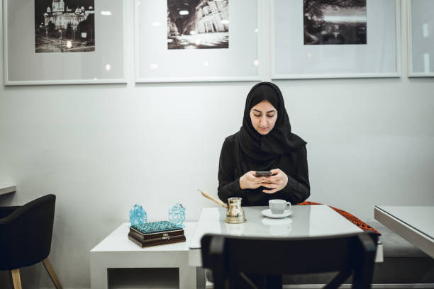 istock Muslim young woman enjoying coffee break at cafe, using mobile phone 978996172