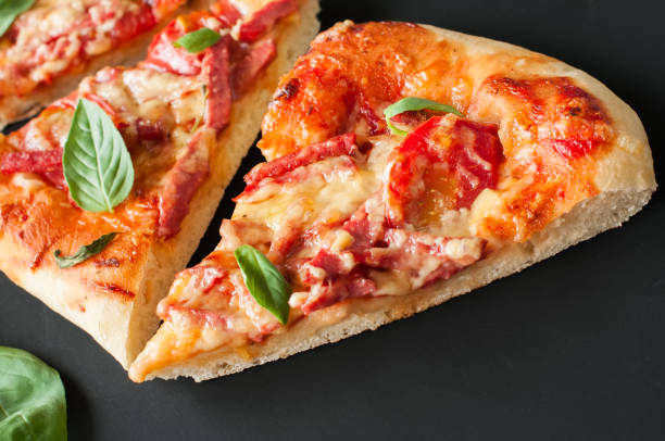 istock Three slices salami mozarella pizza black background. Top view f 978997626