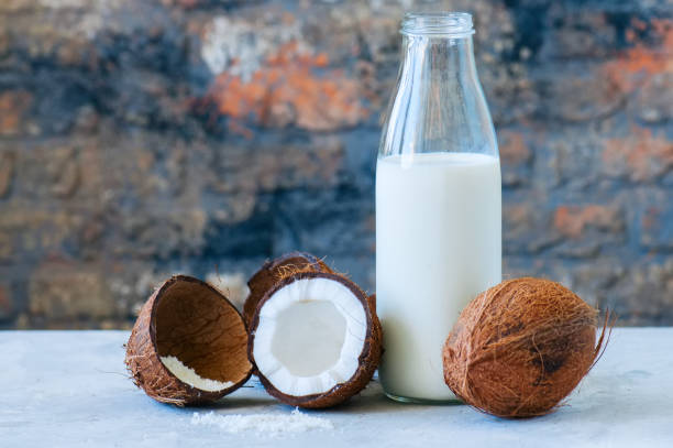 Whole coconuts and coconut products as milk and powder. White st Whole coconuts and coconut products as milk and powder. White stone background. coconut milk photos stock pictures, royalty-free photos & images