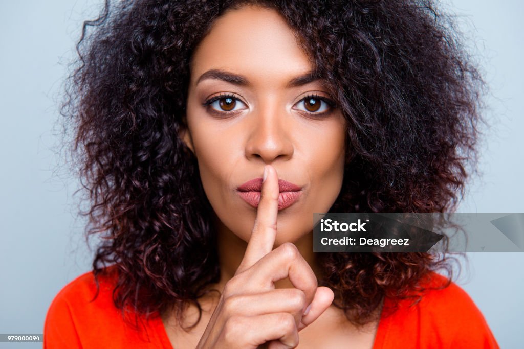 SHH! Closeup retrato de mujer con encanto misteriosa con peinado moderno pidiendo mantener silencio sosteniendo índice en labios regordetes aislados sobre fondo gris - Foto de stock de Dedo sobre labios libre de derechos