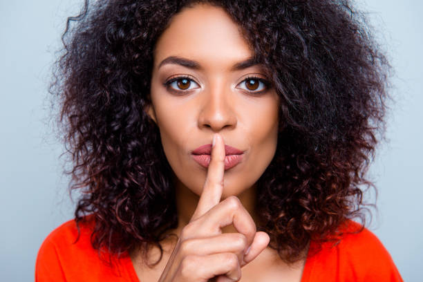 shh! closeup retrato de mujer con encanto misteriosa con peinado moderno pidiendo mantener silencio sosteniendo índice en labios regordetes aislados sobre fondo gris - shes fotografías e imágenes de stock