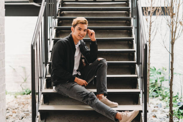 istock Young adult man sitting on staircase looking at camera 979008784