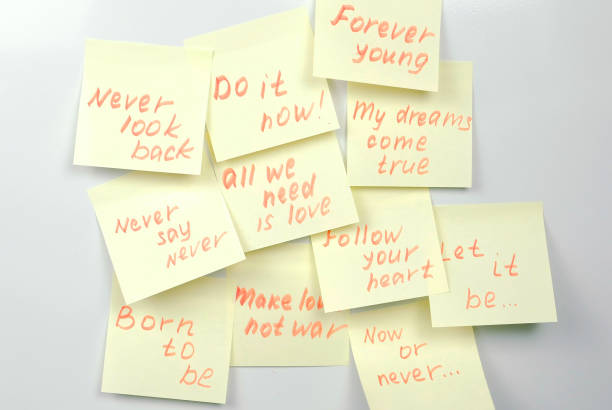 istock Yellow sticker paper sheets with motivation phrases on a white board. 979009152