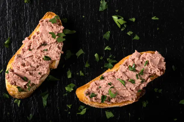 Liverwurst Sandwich with chopped parsley on a dark slate - top view