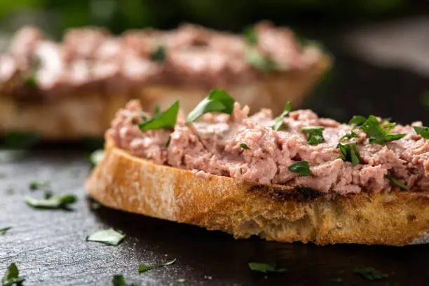 Liverwurst Sandwich with chopped parsley on a dark slate - close up view