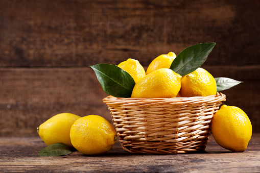 fresh lemons with leaves in a wooden basket