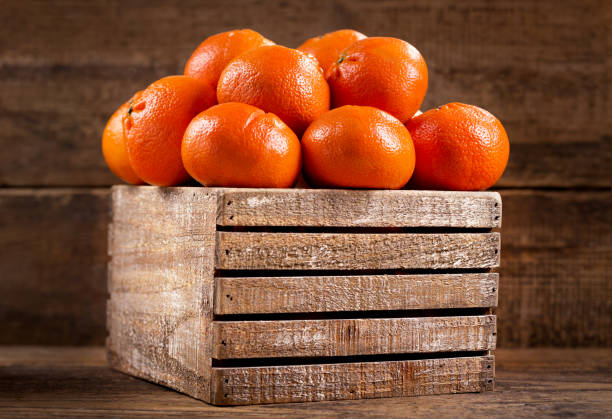 Top view of freshly picked organic tangerines in a wooden crate. Tangerine box