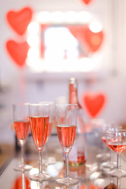 Chapagne wineglasses with pink wine and heart decorations in background. Concept of alcohol and valentine party.